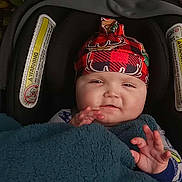 Kaizenn is registered to the contest to win money with this photo: baby, baby_girl_or_boy, blanket, car_seat, child, clothing, cozy, cute, face, greenery, hands, hat, infant, leaves, outdoor, portrait, red, seat, smiling, winter_wear