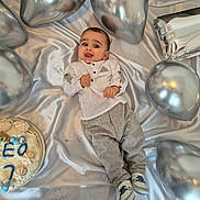 Léo participe au concours pour gagner de l'argent avec cette photo : baby, child, birthday, cake, balloons, silver, satin, celebration, party, smiling, tongue_out, clothing, pants, shirt, footwear, decorations, blue, white, number, name