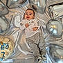 baby, child, birthday, cake, balloons, silver, satin, celebration, party, smiling, tongue_out, clothing, pants, shirt, footwear, decorations, blue, white, number, name