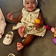 Aiyanna is registered to the contest to win money with this photo: accessory, baby, celebration, child, colorful, couch, cute, dress, easter_egg, foot, happy, headband, indoors, infant, person, playful, shoe, sitting, smiling, toy