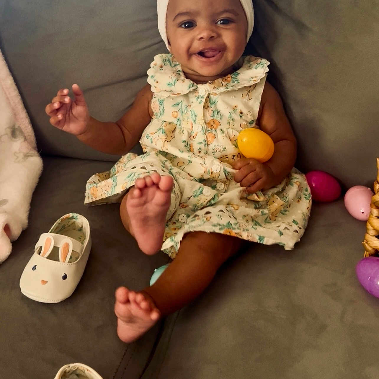 Aiyanna is registered to the contest to win money with this photo: accessory, baby, celebration, child, colorful, couch, cute, dress, easter_egg, foot, happy, headband, indoors, infant, person, playful, shoe, sitting, smiling, toy