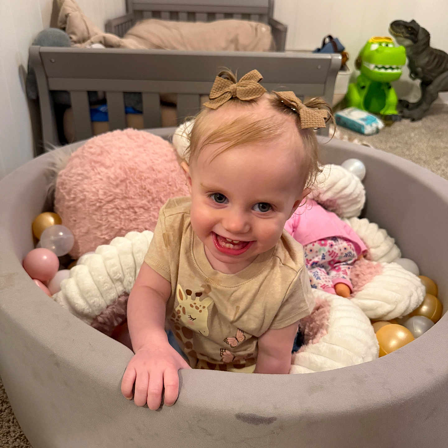 Brylee joined the competition — help win amazing prizes! toddler, child, playpen, toys, dinosaur_toys, bed, nursery, smiling, happy, indoor, carpet, plush_toys, balls, hair_bows, clothing, person, face, baby, cute, play