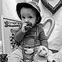 baby, beads, black_and_white, child, clothing, cozy, cute, decoration, face, hand, hat, heart, indoor, love, person, plaid, portrait, sitting, snack, toy