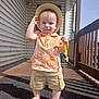 Cris joined the competition — help win amazing prizes! barefoot, child, cute, door, hat, house_siding, orange_shirt, outdoor, person, plaid_mat, porch, shadow, shorts, smiling, standing, summer, sunlight, toddler, toothbrush, wooden_railing