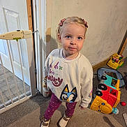 Selene joined the competition — help win amazing prizes! baby_gate, blonde_hair, blue_eyes, carpet, casual_clothing, child, cute, footwear, home, indoor, leggings, person, pigtails, playful, standing, sweater, toddler, toy, toy_truck, wall_scribbles