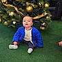 Kayden a rejoint le concours — aidez-le/la à gagner de superbes lots ! baby, child, blue_jacket, christmas_tree, gold_ornaments, ribbon, green_carpet, indoor, festive, holiday, decorations, sitting, curious, smiling, cute, toddler, winter_clothing, bright_colors, holiday_season, celebration