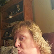 Molly is registered to the contest to win money with this photo: woman, cat, kiss, indoor, furniture, shelf, doll, portrait, affection, pet, hair, face, home_decor, wood, closeup, couch, light, feline, adult, love