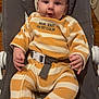 baby, baby_rocker, baby_seat, child, comfortable, curious, cute, face, feet, hands, indoor, infant, onesie, person, smiling, straps, striped_clothing, white, wooden_floor, yellow