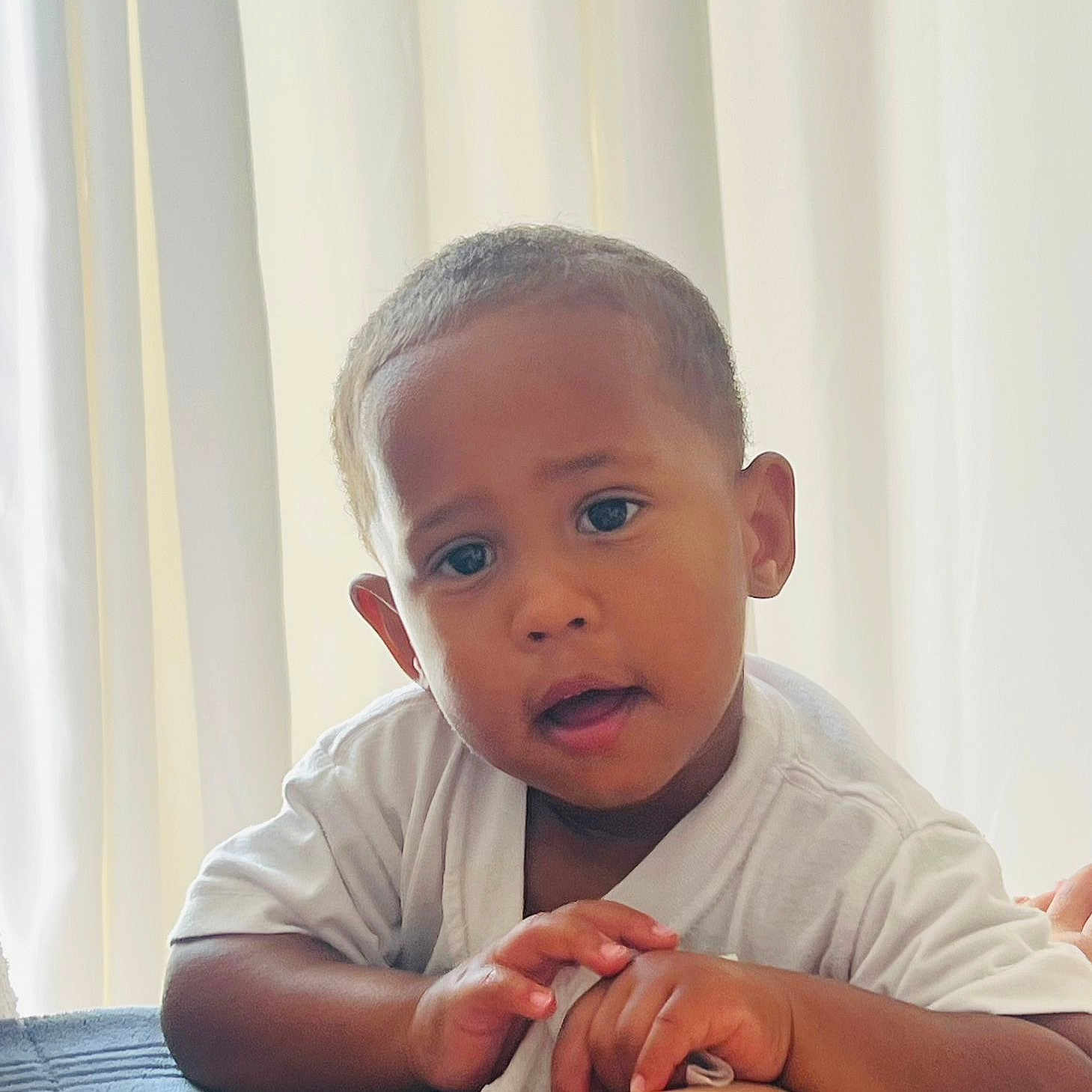 Adael is registered to the contest to win money with this photo: baby, candid, child, closeup, curtains, cute, expression, face, hands, indoor, looking, person, portrait, resting, short_hair, skin, soft_light, toddler, white_shirt, young_child