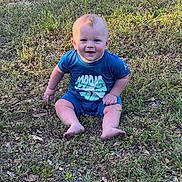 Forrest is registered to the contest to win money with this photo: baby, child, grass, outdoor, smile, blue_clothing, sitting, sunlight, nature, happy, cute, young_child, barefoot, greenery, daylight, grass_field, person, infant, joyful, casual