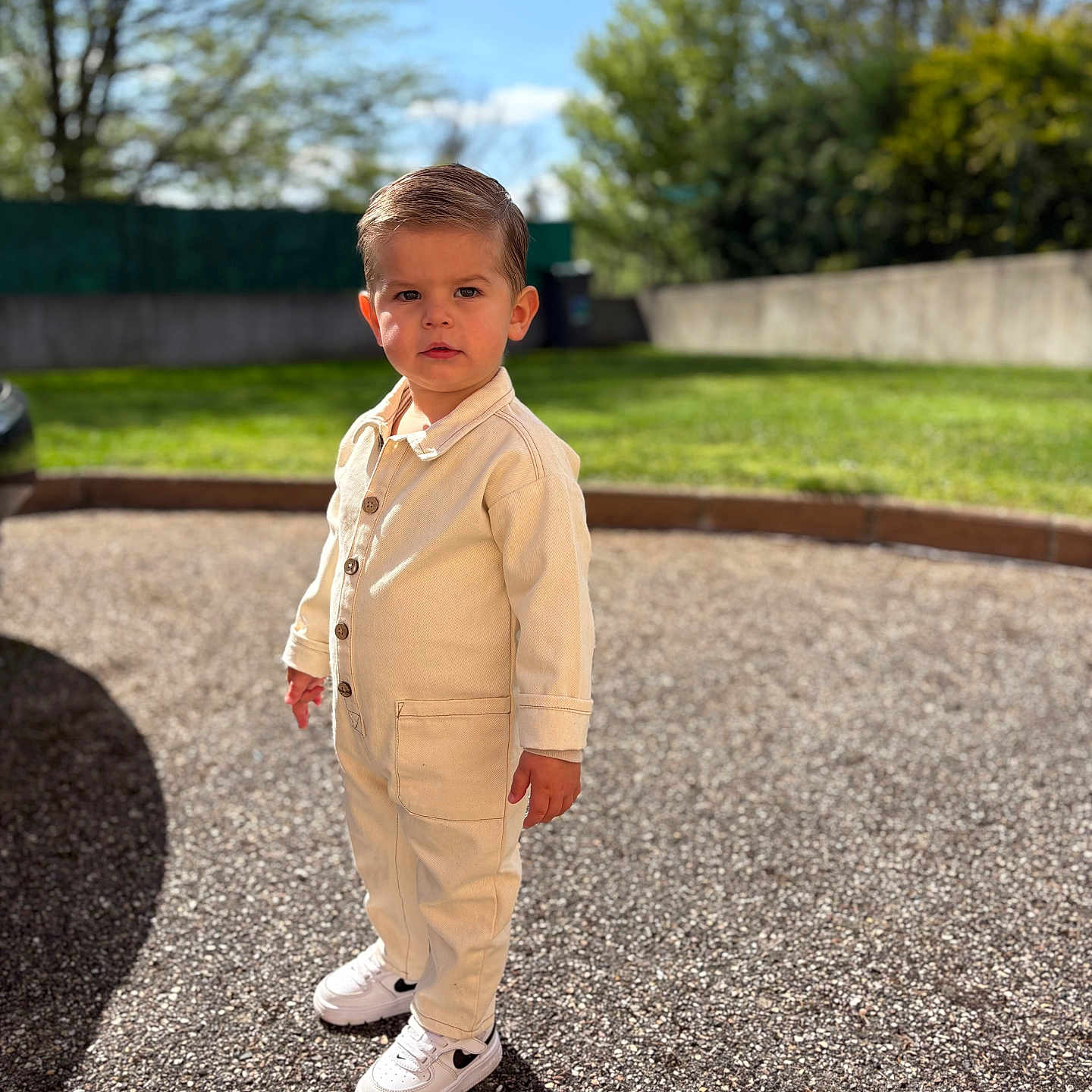 Milann a rejoint le concours — aidez-le/la à gagner de superbes lots ! asphalt, boy, casual, child, clothing, curious, daytime, fence, greenery, hairstyle, jumpsuit, outdoor, portrait, shadow, sneakers, standing, sunlight, toddler, trees, young