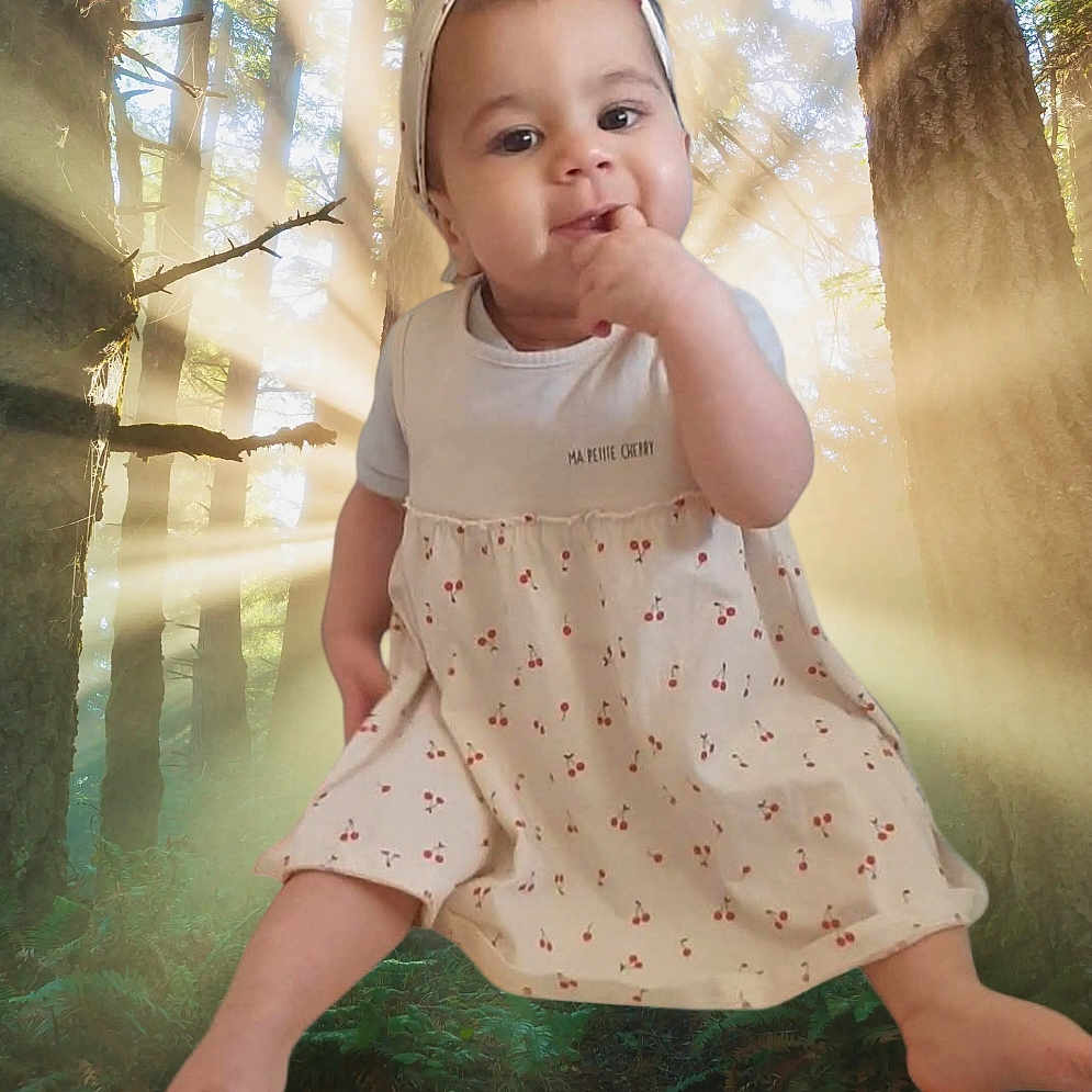 Lila participe au concours pour gagner de l'argent avec cette photo : baby, clothing, dress, face, grass, head, land, nature, outdoors, person, photography, plant, portrait, sitting, sky, sleeve, sunlight, tree, vegetation, woodland