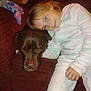 child, dog, pajamas, couch, indoor, brown_dog, red_couch, child_hugging_dog, cozy, relaxed, pet, companion, furniture, casual, home, cute, snuggle, comfort, happy, young_girl