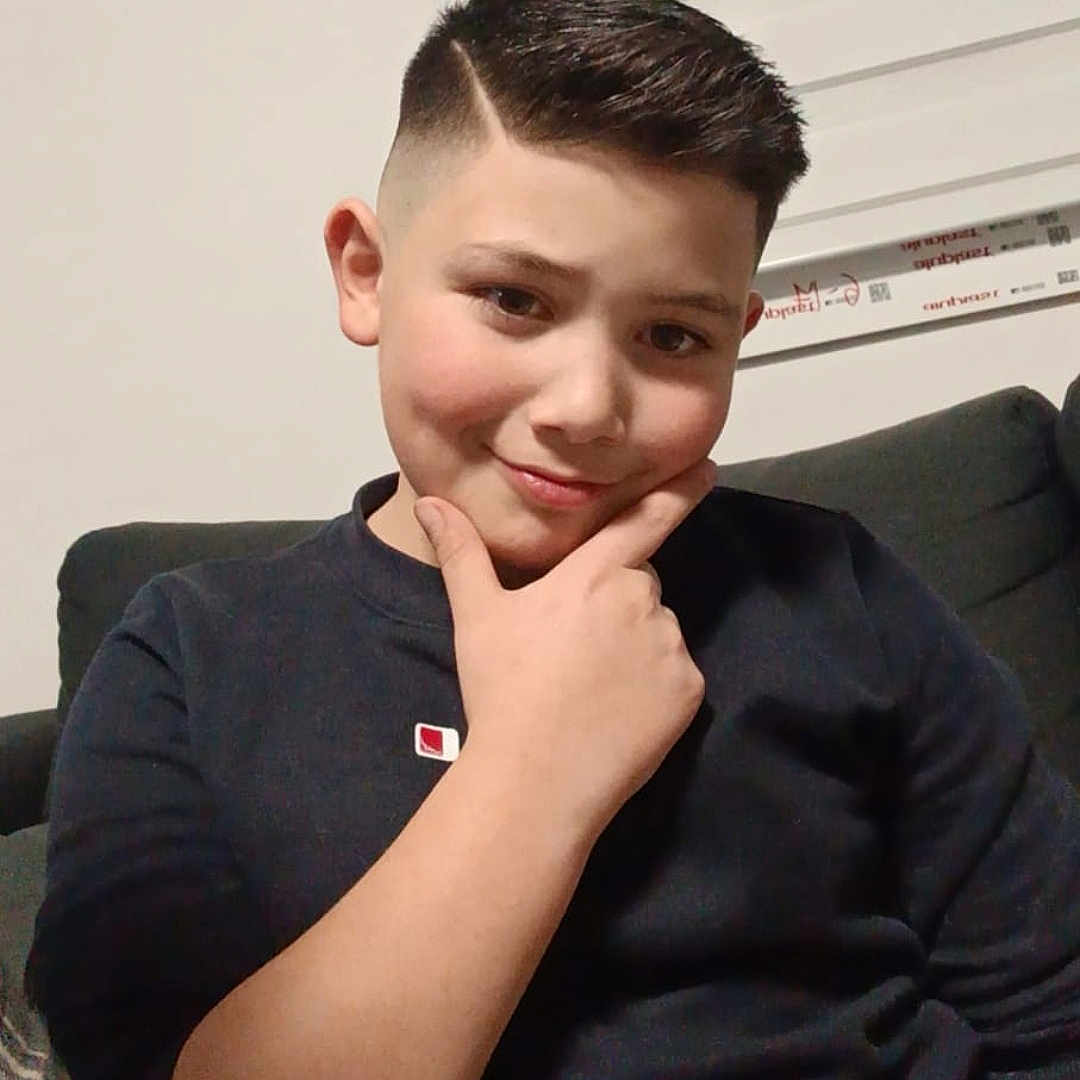 Anil participe au concours pour gagner de l'argent avec cette photo : black_shirt, boy, casual, child, couch, cozy, cute, expression, face, haircut, hand_on_chin, home, indoors, person, portrait, seated, short_hair, smile, thinking_pose, young