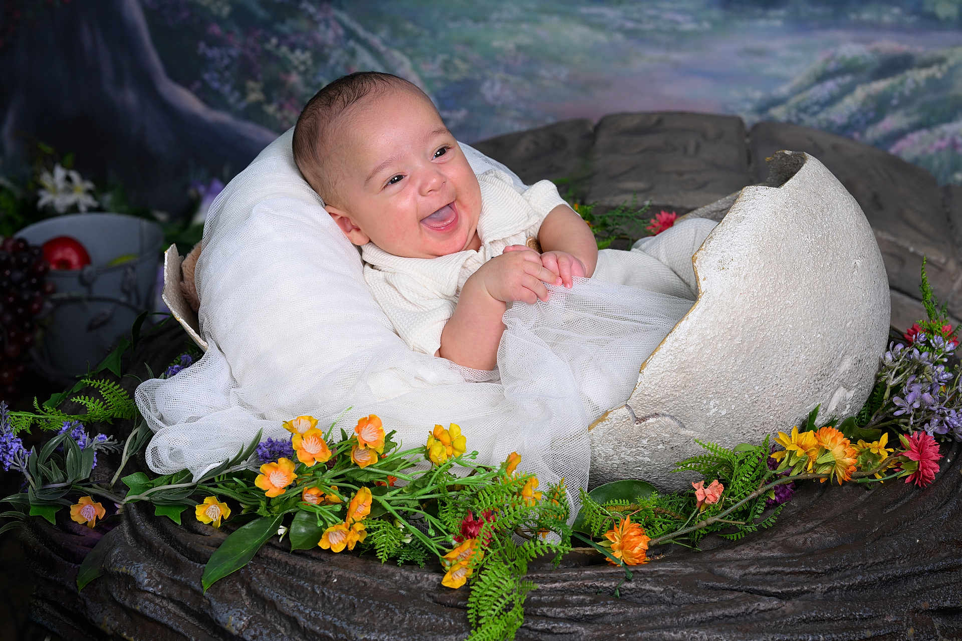 Austin is registered to the contest to win money with this photo: baby, infant, smiling, eggshell, flowers, greenery, prop, portrait, cute, happy, white_clothing, fabric, nature_theme, studio_photo, background, artificial, scene, child, nest, playful