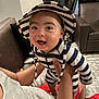 Emiliano joined the competition — help win amazing prizes! baby, child, striped_hat, striped_clothing, smiling, happy, indoor, person, adult_hand, couch, leather_chair, curtain, floor, playful, portrait, infant, hat, holding, expression, casual