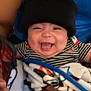 Emiliano joined the competition — help win amazing prizes! baby, child, smiling, black_beanie, striped_shirt, blanket, mickey_mouse, person, happy, infant, holding, blue_tank_top, hand, cute, indoors, portrait, face, clothing, toddler, joyful