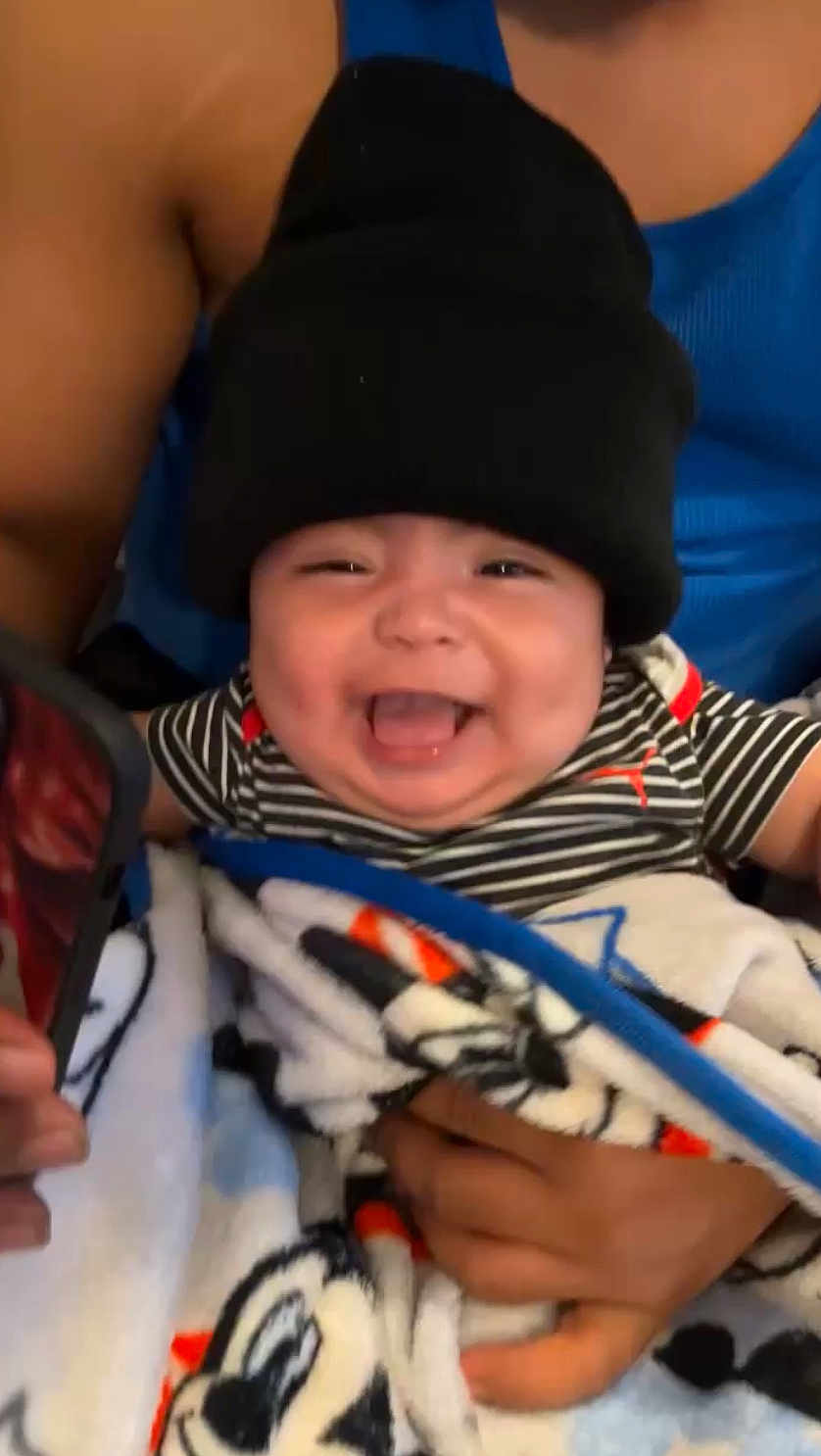 Emiliano joined the competition — help win amazing prizes! baby, child, smiling, black_beanie, striped_shirt, blanket, mickey_mouse, person, happy, infant, holding, blue_tank_top, hand, cute, indoors, portrait, face, clothing, toddler, joyful