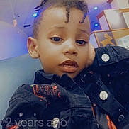 Joshua joined the competition — help win amazing prizes! child, face, person, indoor, hairstyle, jacket, black_clothing, casual_pose, curious_expression, modern_interior, colorful_lighting, social_media_interface, timestamp, portrait, young, dreadlocks, buttons, sitting, head, looking_at_camera