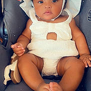 Amiri is registered to the contest to win money with this photo: baby, bodypart, bonnet, cap, clothing, costume, diaper, dress, face, finger, hand, hat, head, person, photography, portrait, sitting, sunhat, t_shirt, transportation