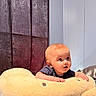 baby, infant, plush, pillow, curious, indoor, child, soft_toy, cushion, face, expression, person, toddler, bedroom, furniture, blanket, head, clothing, young_child, cute