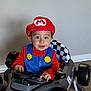 Cannon is registered to the contest to win money with this photo: blue_overalls, child, costume, floor, furniture, halloween, happy, hat, holiday_decor, indoor, kitchen, lights, mario, playful, pumpkins, race_car, red_clothing, smiling, toddler, toy_car