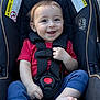 baby, barefoot, blue_pants, car_seat, child, cute, grass, happy, harness, infant, outdoor, person, portrait, red_shirt, safety, seatbelt, sidewalk, smiling, sunlight, young_child
