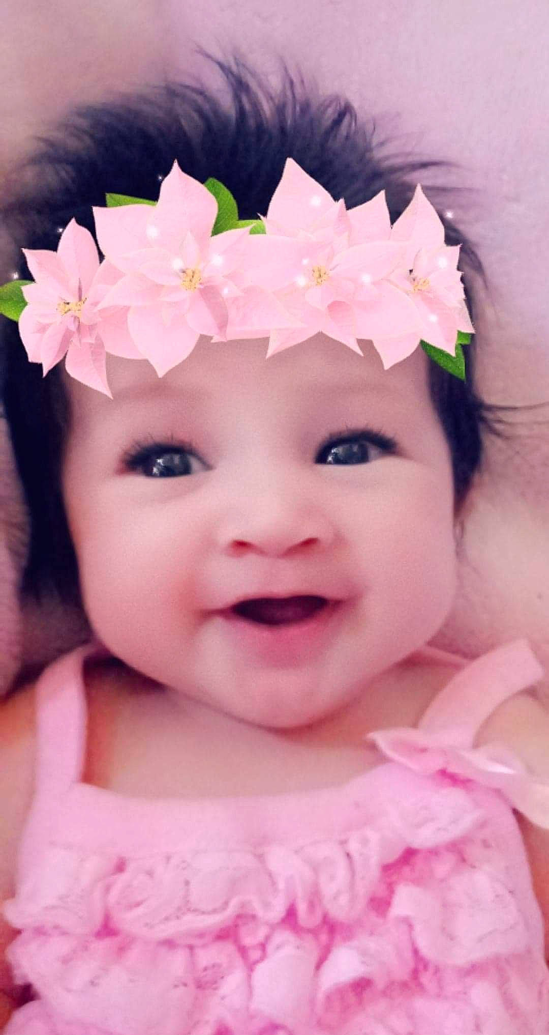 Cynthia is registered to the contest to win money with this photo: baby, cheek, child, close_up, eye, face, flower, hair_accessory, head, headband, headgear, headpiece, iris, person, petal, pink, plant, product, skin, smile