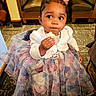 baby, booth, butterfly_pattern, carpet, chair, child, clothing, curious, curly_hair, cute, dress, girl, indoor, pigtails, portrait, restaurant, seated, snack, table, toddler