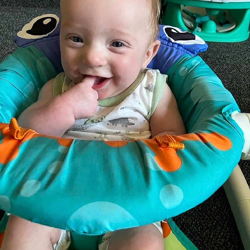 Harrison joined the competition — help win amazing prizes! baby, child, infant, smiling, sitting, baby_seat, colorful, finger_in_mouth, happy, indoor, carpet, clothing, toy, play, cute, person, young_child, home, comfort, seat