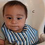 baby, child, high_chair, bib, striped_bib, food_on_face, cute, infant, indoor, person, portrait, feeding_time, curious, young_child, sitting, face, head, expression, clothing, closeup