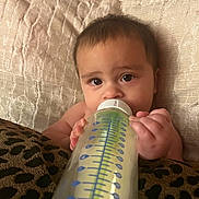 Levi is registered to the contest to win money with this photo: baby, bottle, milk, infant, bed, pillow, blanket, hand, face, eyes, skin, cute, child, feeding, indoors, rest, comfort, closeup, person, young