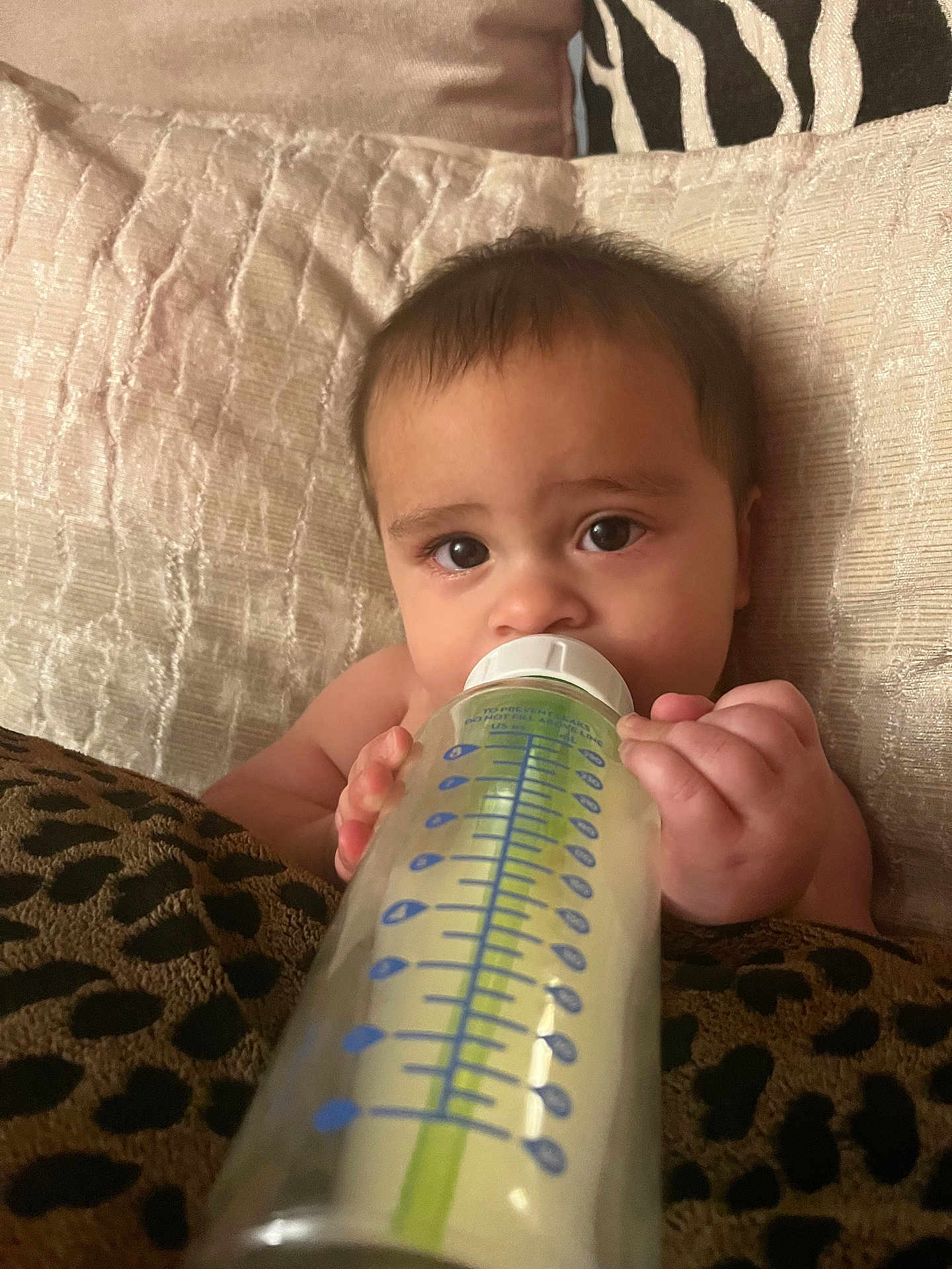 Levi is registered to the contest to win money with this photo: baby, bottle, milk, infant, bed, pillow, blanket, hand, face, eyes, skin, cute, child, feeding, indoors, rest, comfort, closeup, person, young