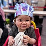 toddler, child, smiling, crown, blanket, chair, indoor, happy, face, person, clothing, toy, seat, cute, baby, holding, portrait, infant, soft_toy, playful