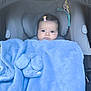 baby, blanket, blue, stroller, infant, child, face, hair_clip, seated, cozy, soft, comfort, cute, outdoor, person, head, clothing, infant_seat, young_child, wrapped