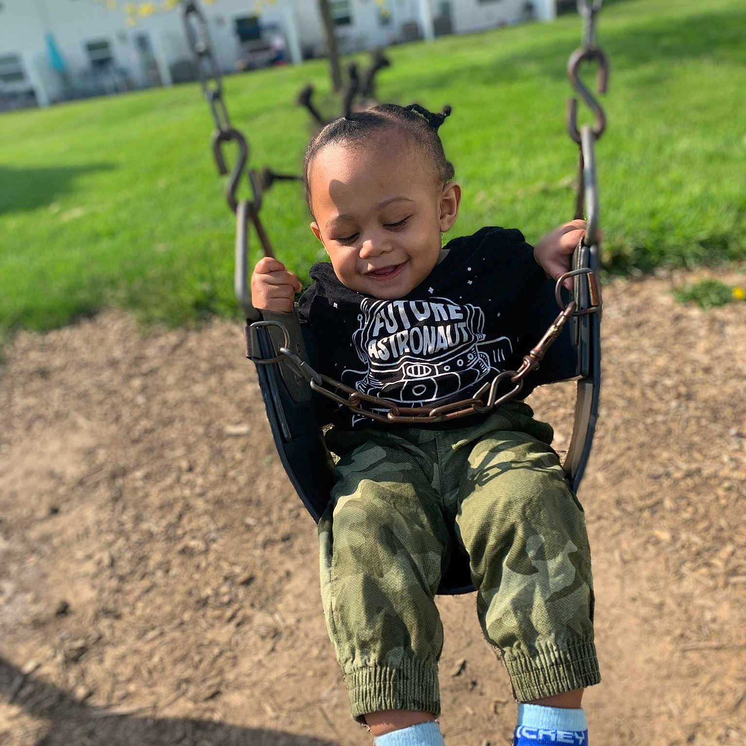 Messiah is registered to the contest to win money with this photo: child, city, fun, happy, joy, outdoor_play_equipment, person, play, playground, public_space, recreation, smile, swing, toddler, tree