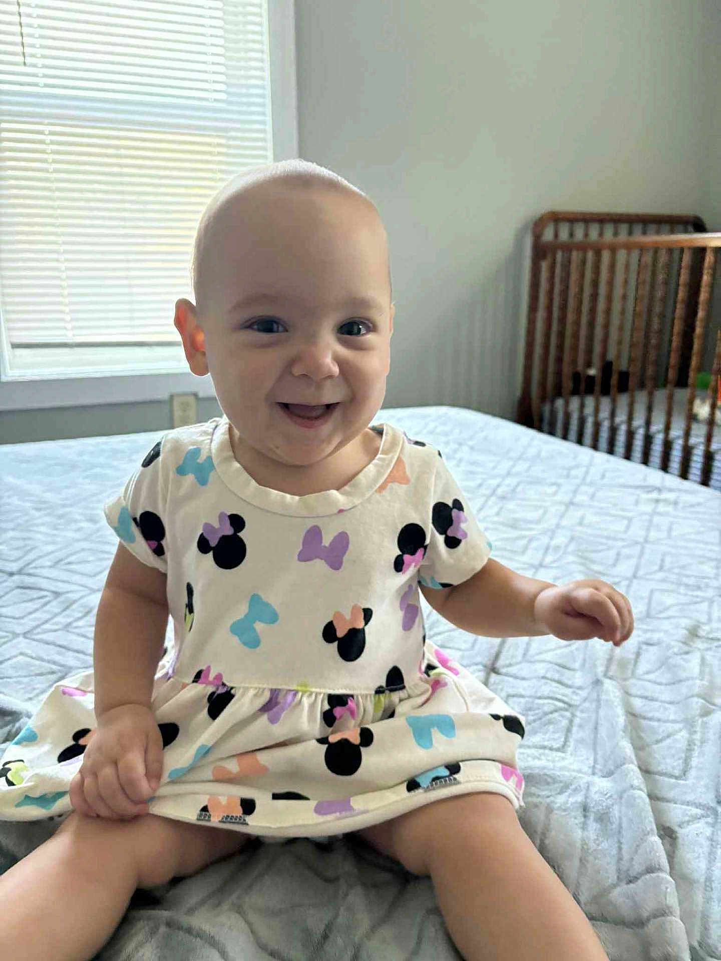 Brooklyn joined the competition — help win amazing prizes! baby, child, smiling, dress, bed, blanket, window, crib, indoor, person, cute, happy, sitting, infant, mickey_mouse, pattern, room, light, clothing, playful