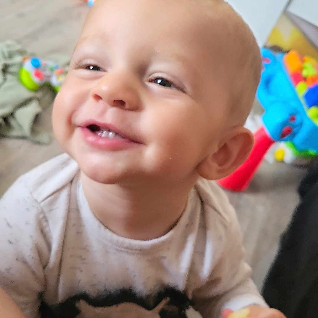 Leo participe au concours pour gagner de l'argent avec cette photo : baby, cheerful, child, clothing, eyes, face, floor, furniture, hand, happy, head, indoor, mouth, person, playtime, smiling, snack, toddler, toy, young