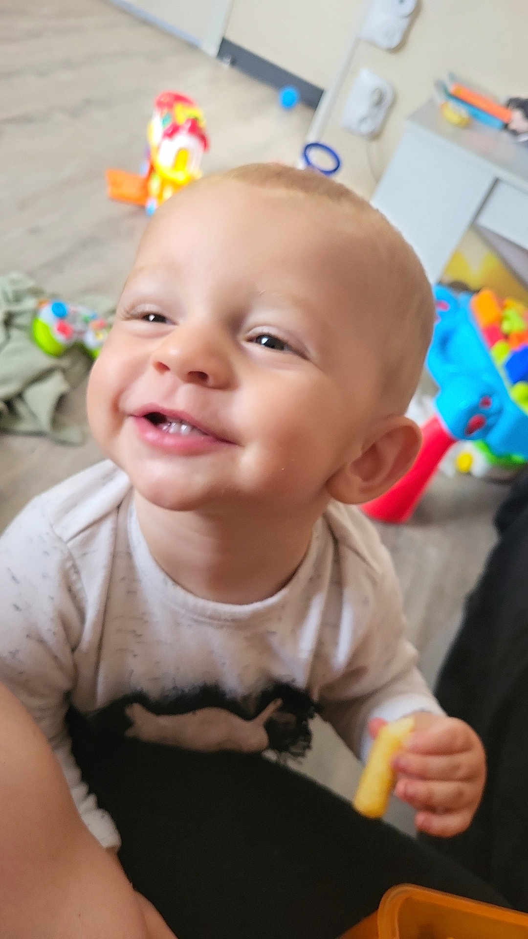 Leo participe au concours pour gagner de l'argent avec cette photo : toddler, smiling, indoor, toy, child, snack, happy, face, person, furniture, floor, clothing, hand, head, eyes, mouth, cheerful, baby, playtime, young