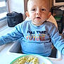 Leo a rejoint le concours — aidez-le/la à gagner de superbes lots ! toddler, child, high_chair, plate, pasta, ham, blue_sweatshirt, indoor, window, computer, table, food, meal, person, face, expression, home, kitchen, furniture, sitting