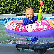 Leo participe au concours pour gagner de l'argent avec cette photo : toddler, child, pool, inflatable_float, water, toy, hammer, summer, outdoor, greenery, swimming, play, fun, sunlight, blue_shirt, pink_float, cartoon_characters, water_toy, baby, happy