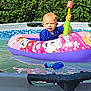 toddler, child, pool, inflatable_float, water, toy, hammer, summer, outdoor, greenery, swimming, play, fun, sunlight, blue_shirt, pink_float, cartoon_characters, water_toy, baby, happy