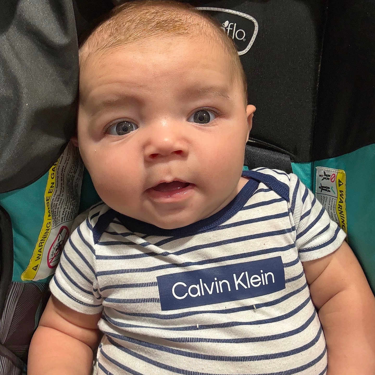 Noah is registered to the contest to win money with this photo: baby, child, infant, striped_clothing, calvin_klein, car_seat, warning_label, cute, curious, blue_eyes, short_hair, chubby_cheeks, sitting, close_up, portrait, indoor, casual, young, person, smiling