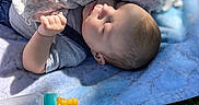Noah is registered to the contest to win money with this photo: baby, blanket, bottle, child, cute, daylight, face, grass, infant, outdoor, peaceful, person, portrait, resting, sleeping, soft, sunlight, toddler, toy, quilt