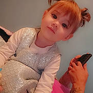 Amelia joined the competition — help win amazing prizes! bed, blanket, blue, casual, child, curious, cute, double_buns, dress, girl, hairstyle, hand, indoor, long_sleeve, person, phone, pink, portrait, soft_lighting, tattoo