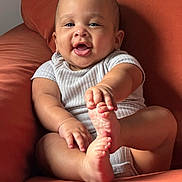 Romeo joined the competition — help win amazing prizes! baby, child, clothing, couch, cute, expression, foot, furniture, hand, happy, indoors, infant, orange, person, portrait, relaxing, seated, short_sleeve, skin, smiling