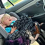 toddler, child, car_seat, blanket, blue_shirt, brown_boots, car_interior, seatbelt, window, bottle, happy, smiling, blond_hair, clothing, seat, door, plastic_bottle, road_trip, travel, casual