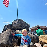 Caden joined the competition — help win amazing prizes! toddler, child, rocks, flag, american_flag, sky, outdoor, sunny, person, man, woman, building, car, clothing, shorts, shirt, pointing, blonde_hair, nature, casual