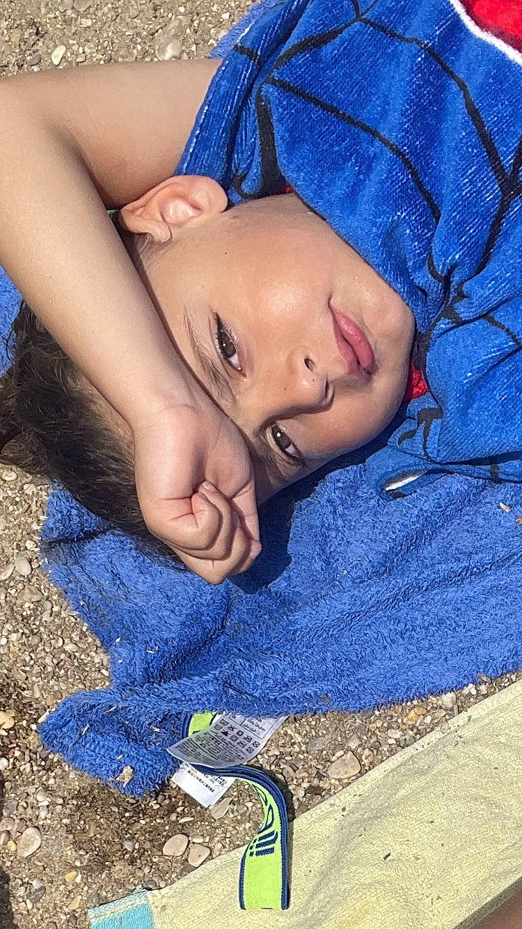 Sandro participe au concours pour gagner de l'argent avec cette photo : abdomen, blue, chest, child, comfort, electric_blue, foot, fun, grass, headwear, human_leg, leg, leisure, mouth, nail, pattern, person, sand, sitting, soil