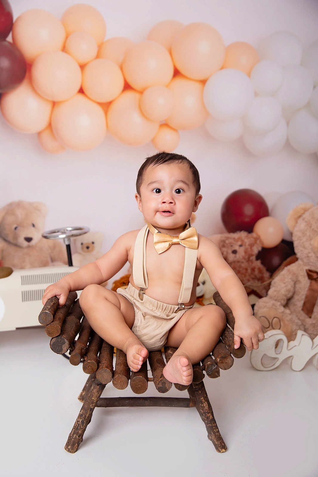 Sebastian joined the competition — help win amazing prizes! baby, child, teddy_bear, balloon, chair, bow_tie, suspenders, wooden_chair, plush_toy, party_decor, smiling, cute, indoor, portrait, person, celebration, baby_clothing, floor, background, happy
